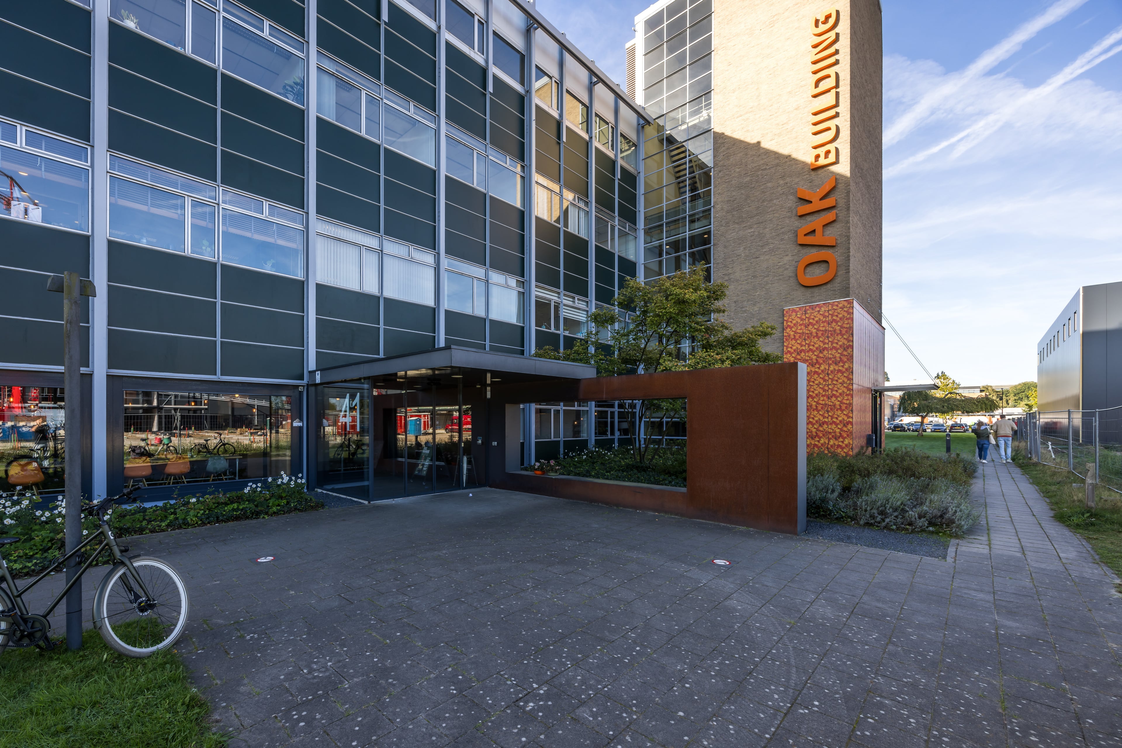 Entree van OAK Building met de oranje letters OAK Building op de bakstenen toren