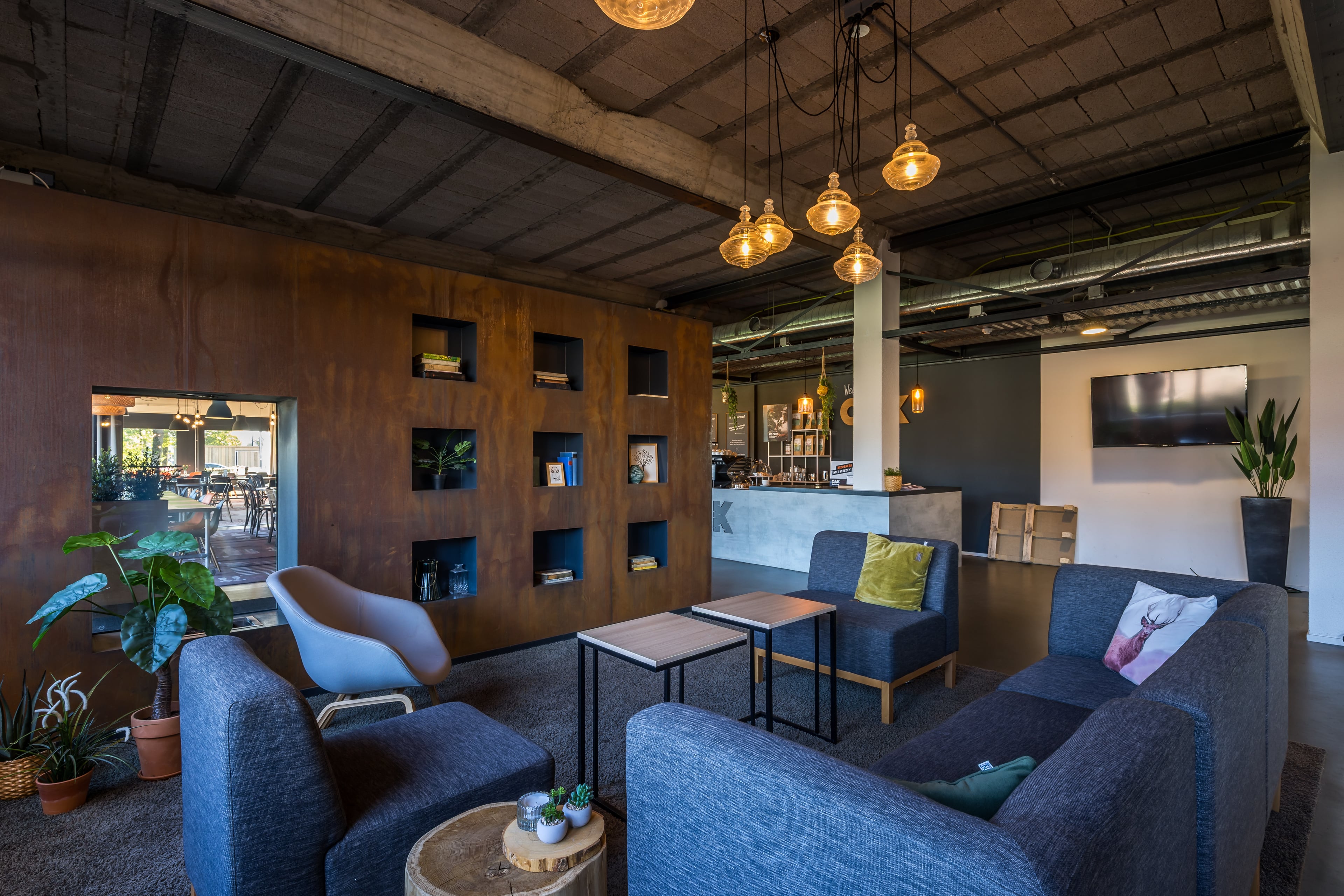 Loungehoek met banken en fauteuils voor een houten wand met open vakken